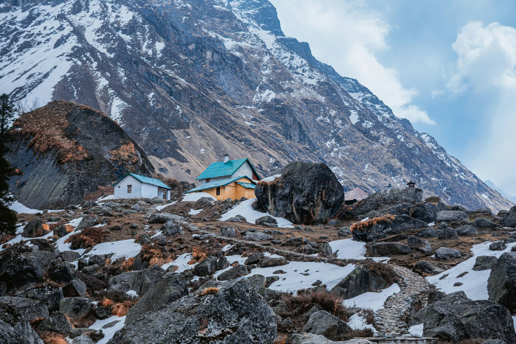 Houses on snow-covered ground below the mountains in Himachal Pradesh