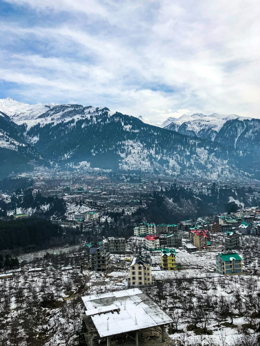 A hill town set below snow-covered mountains near Manali, Himachal Pradesh