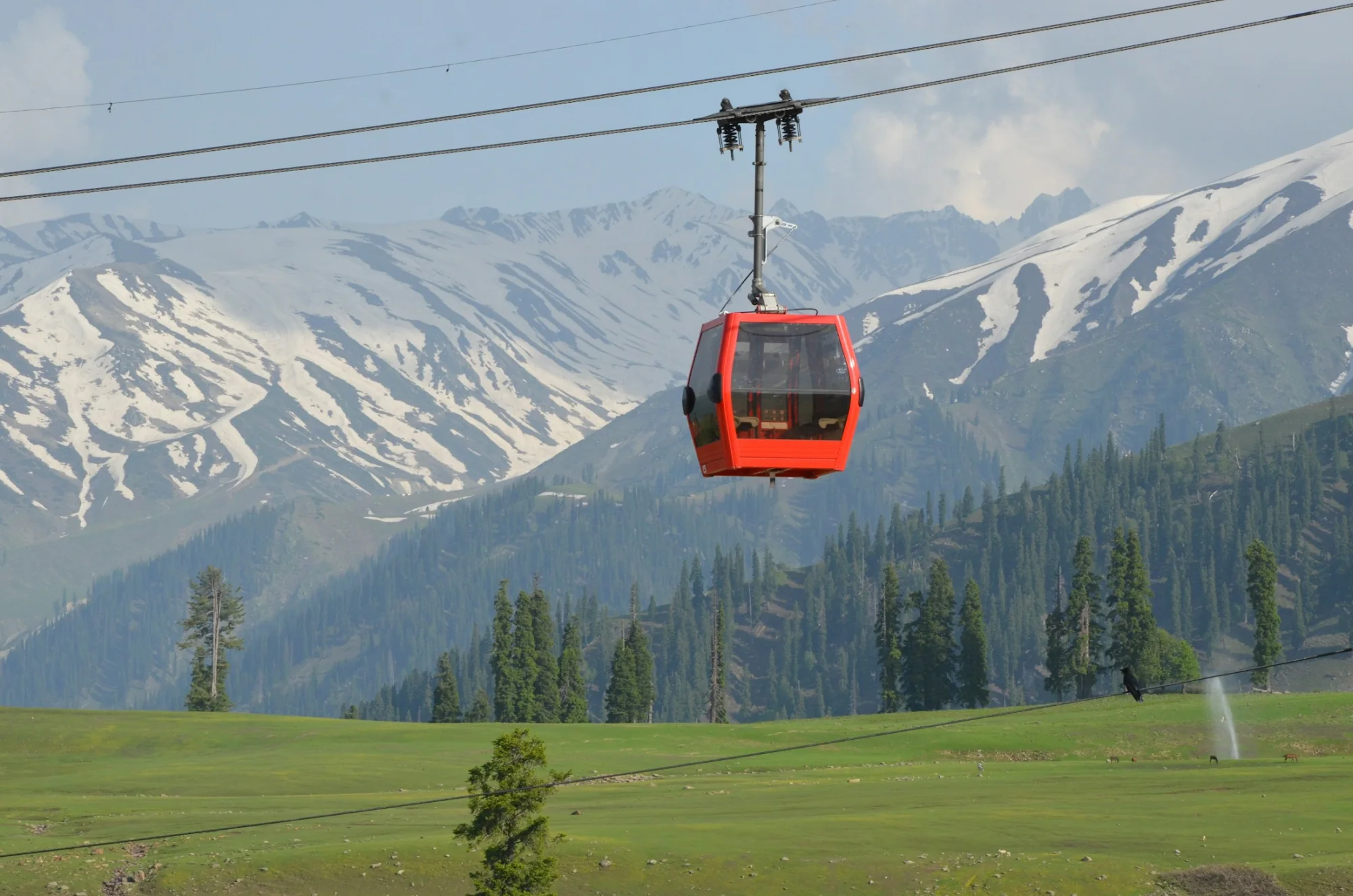 The red Gulmarg Gondola cable car above the snow and pines of Kashmir