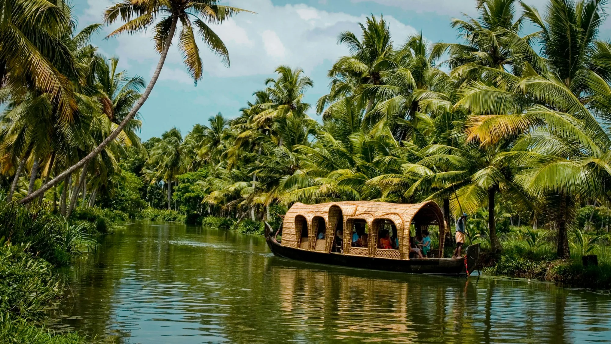 A traditional kettuvallam houseboat on the palm-lined Kerala backwaters
