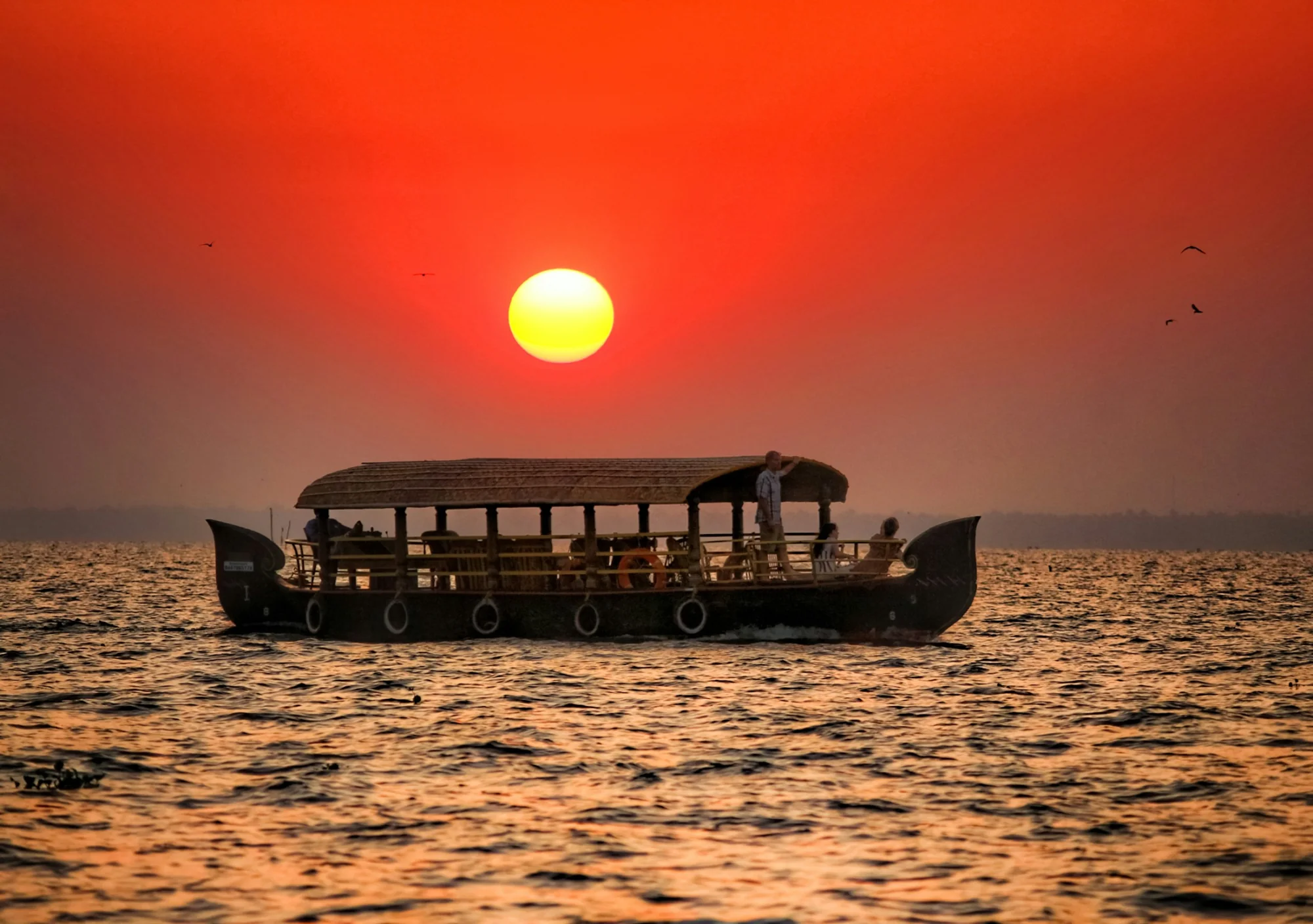 Sunset over the Kerala backwaters with a houseboat silhouette