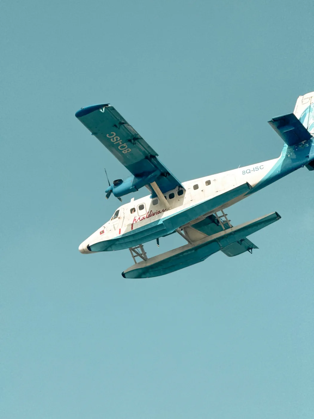 A seaplane flying over the blue skies of the Maldives