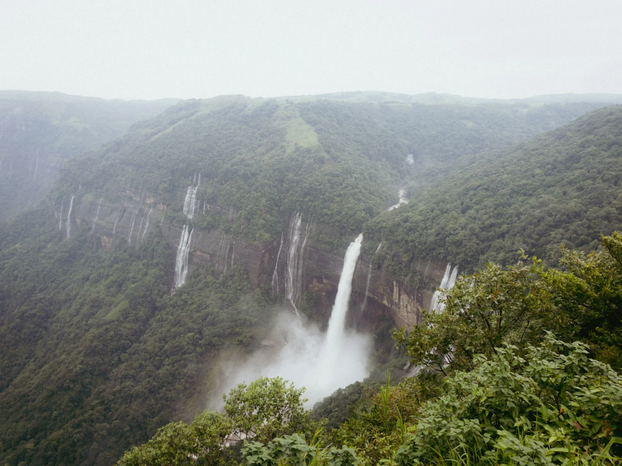 A tall waterfall plunging into a forested gorge in Meghalaya