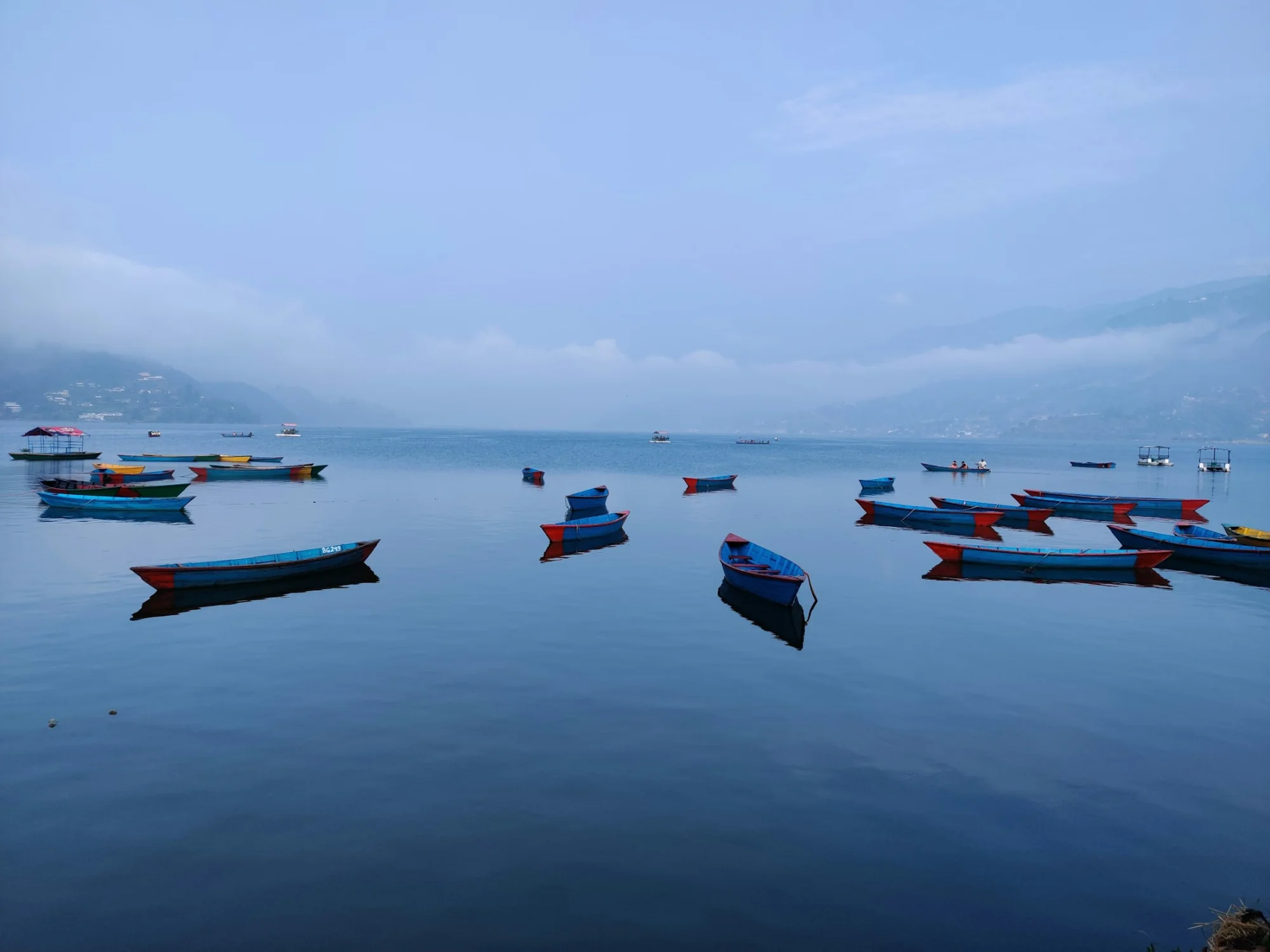 Boats on Phewa Lake below the mountains at Pokhara, Nepal