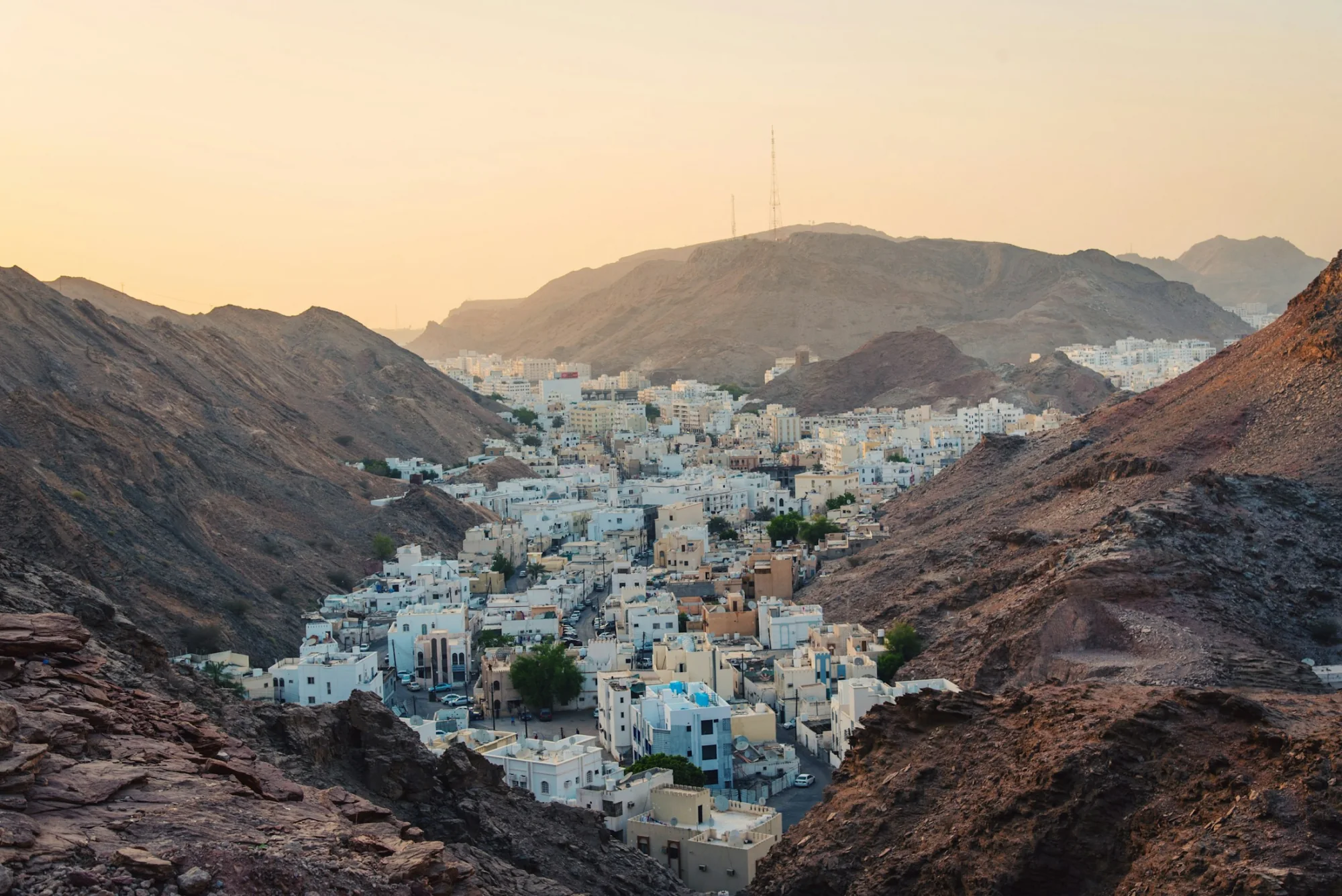 White Omani buildings beneath rocky cliffs in Muscat, Oman