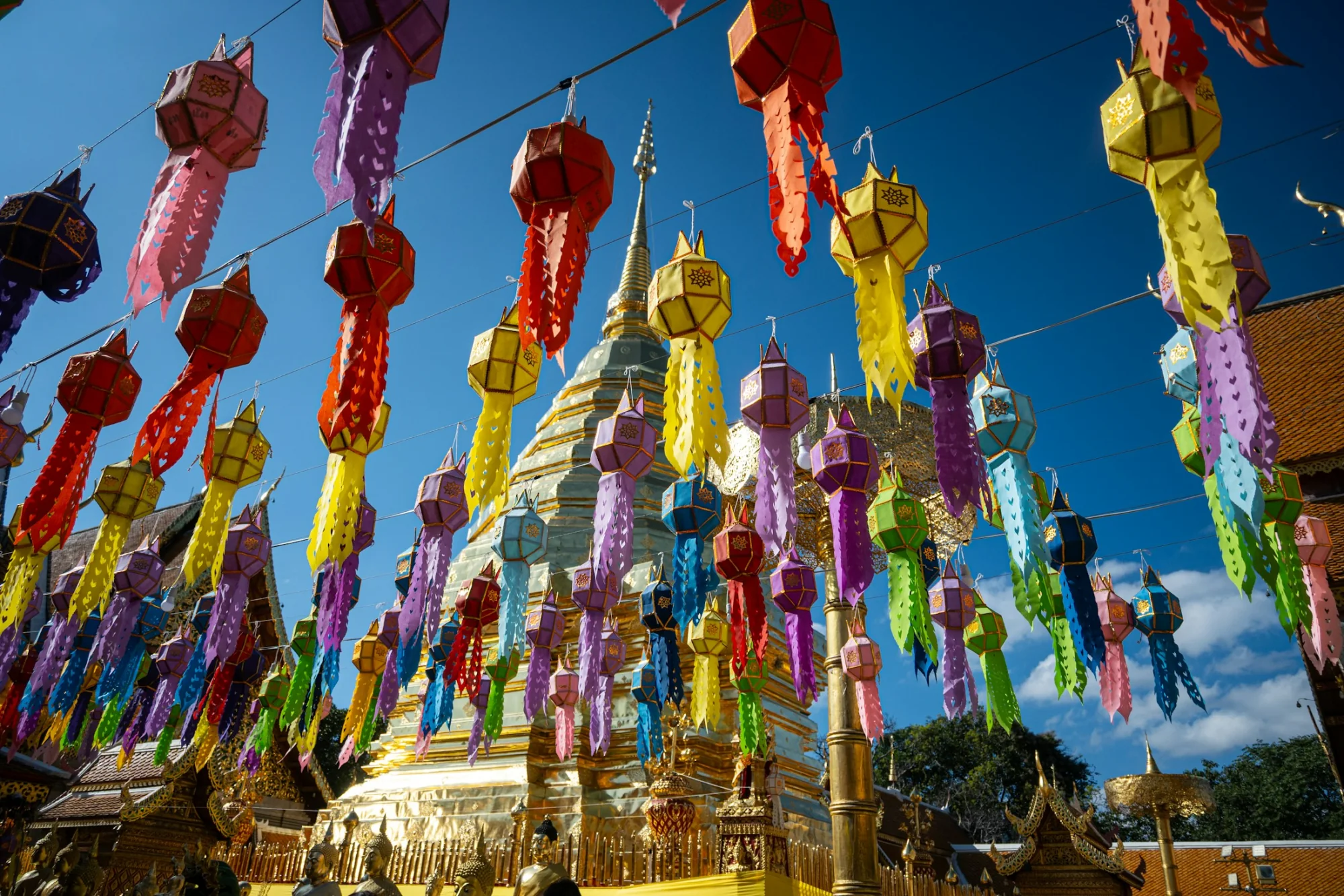 Colourful lanterns hanging before a golden temple in Chiang Mai, Thailand
