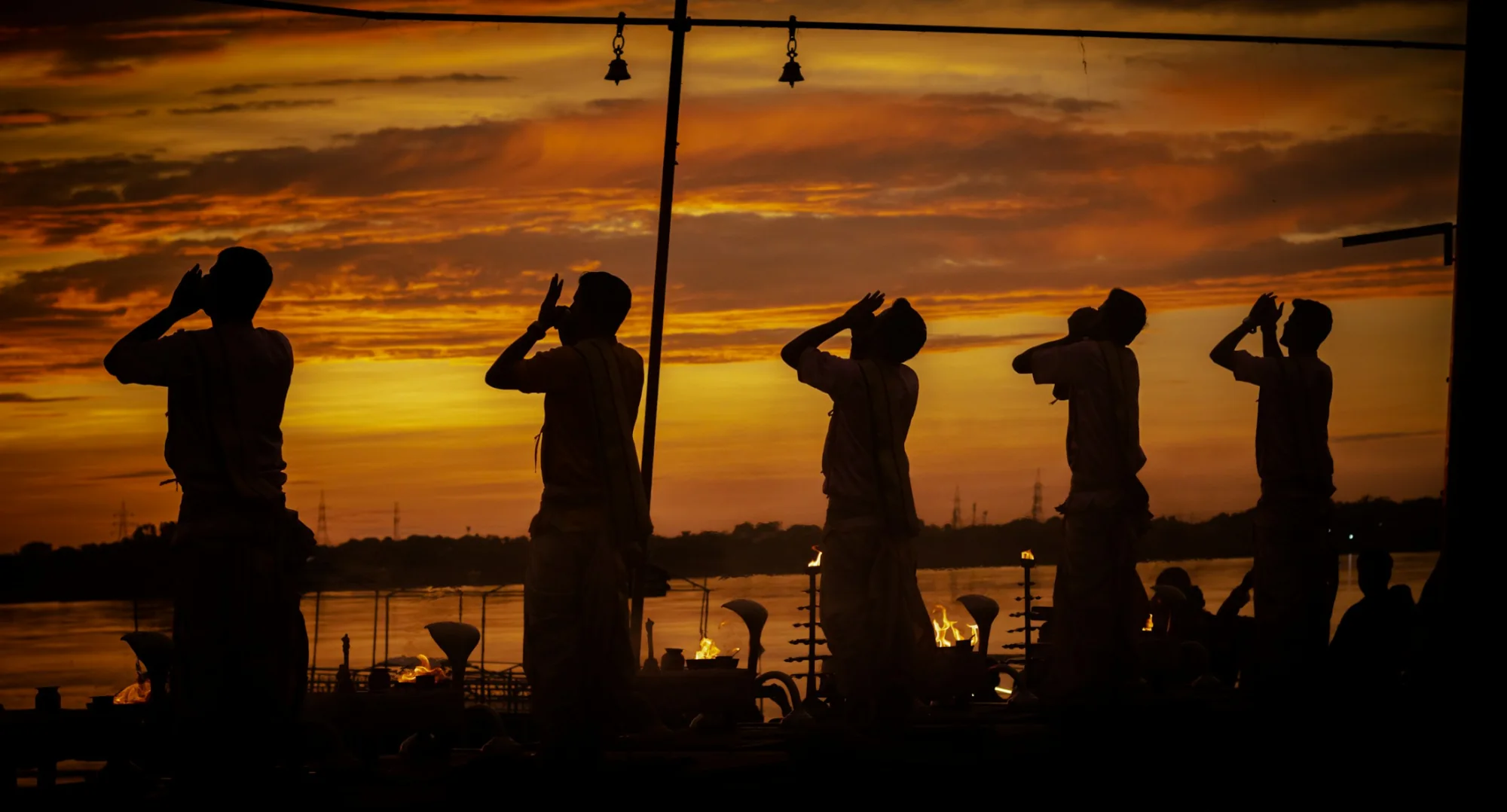 Silhouetted priests performing the Ganga Aarti ceremony at sunset in Varanasi