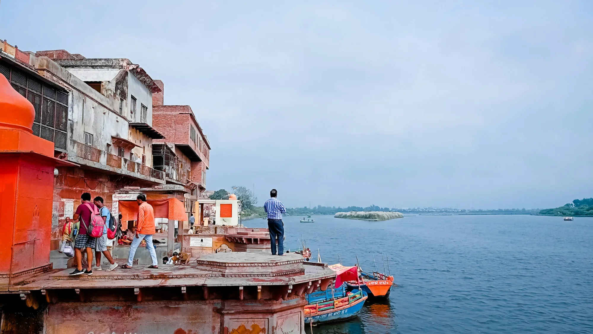 A saffron-coloured wooden boat carrying pilgrims on the Ganges at Varanasi